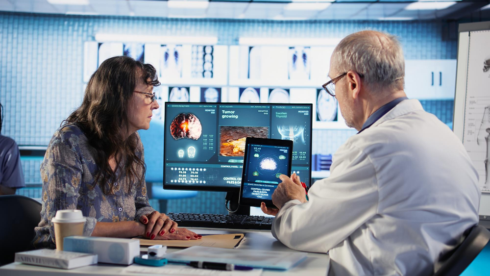 Doctor consulting with a patient while analyzing digital health data on screen