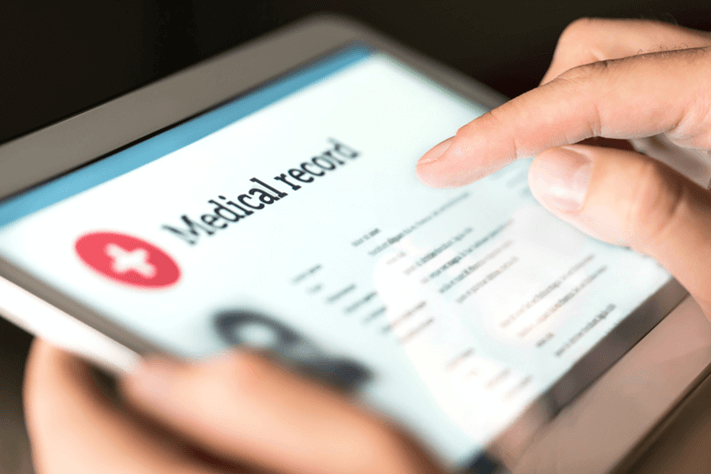 Close-up of a hand interacting with a medical record application on a tablet screen.