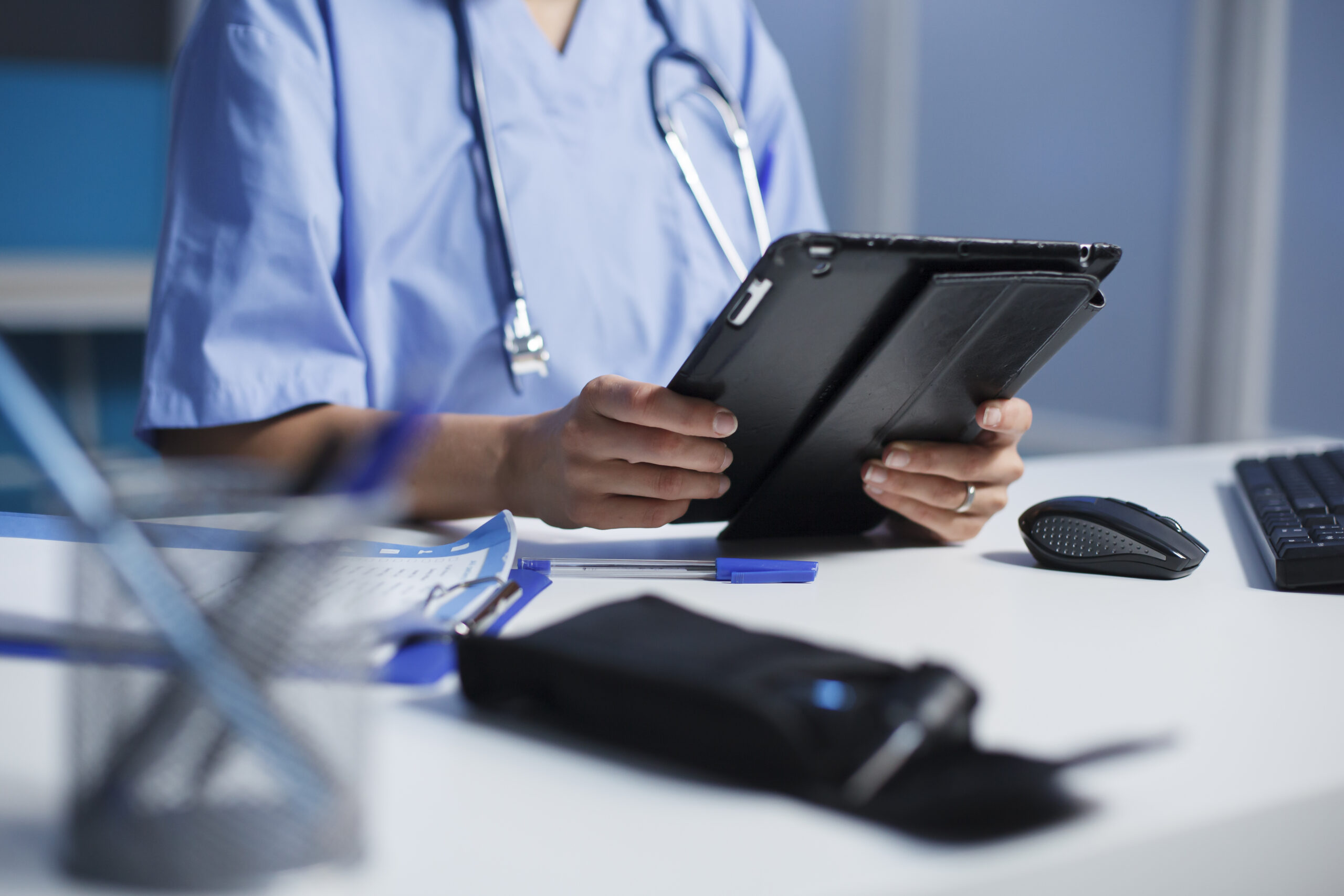 Nurse using mobile tablet for patient care at bedside